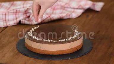 女人装饰和洒坚果顶部巧克力慕斯蛋糕。